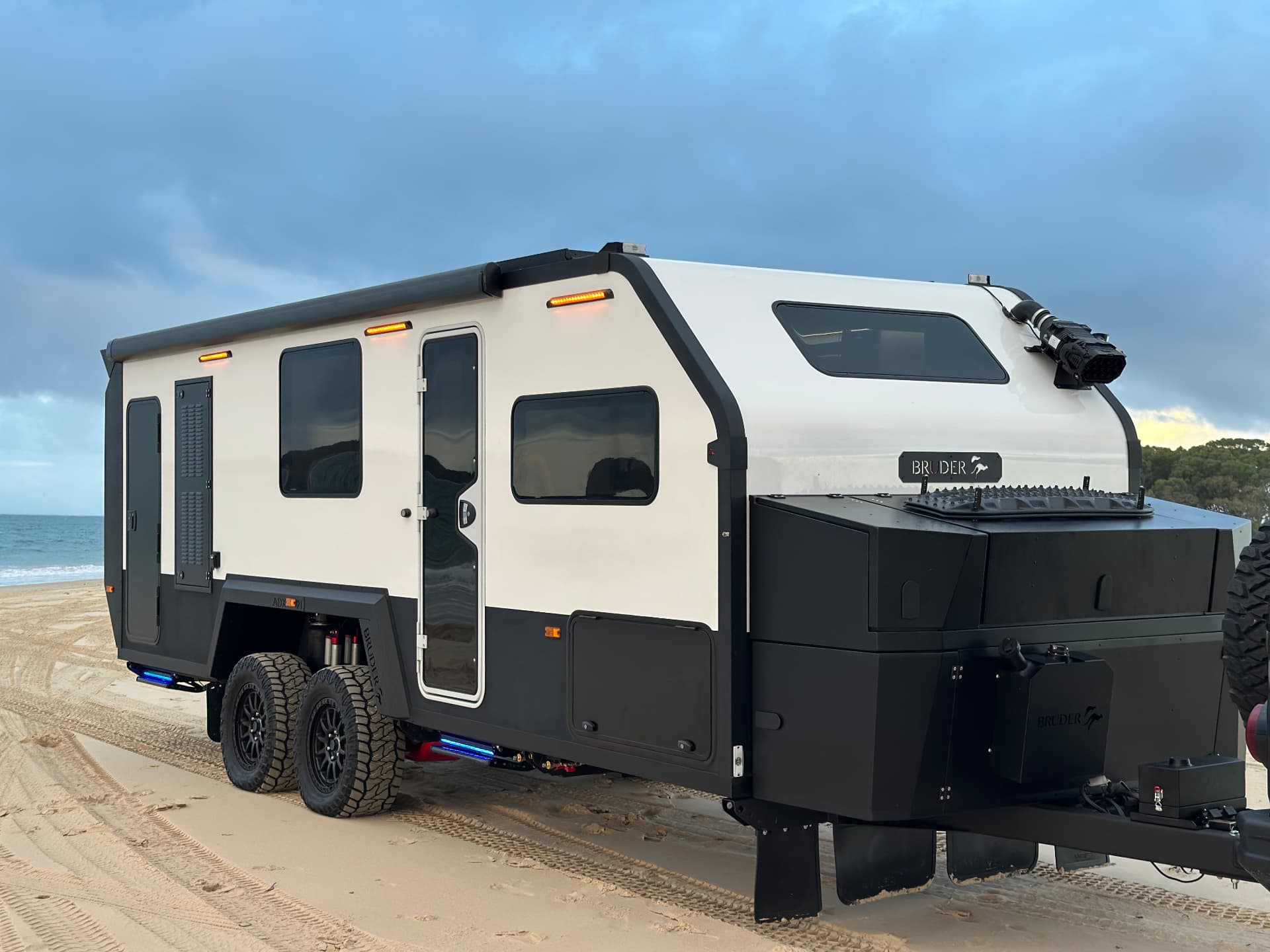 Bruder ADX-21 parked on the sand at dusk with the ocean behind