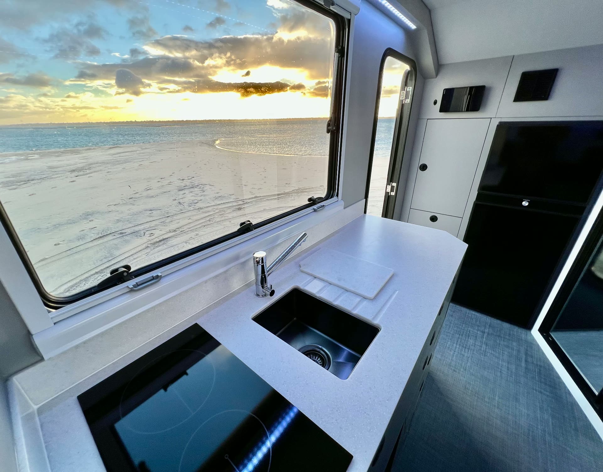 EXP-8 interior galley with induction cooktop and sunset beach view through the window