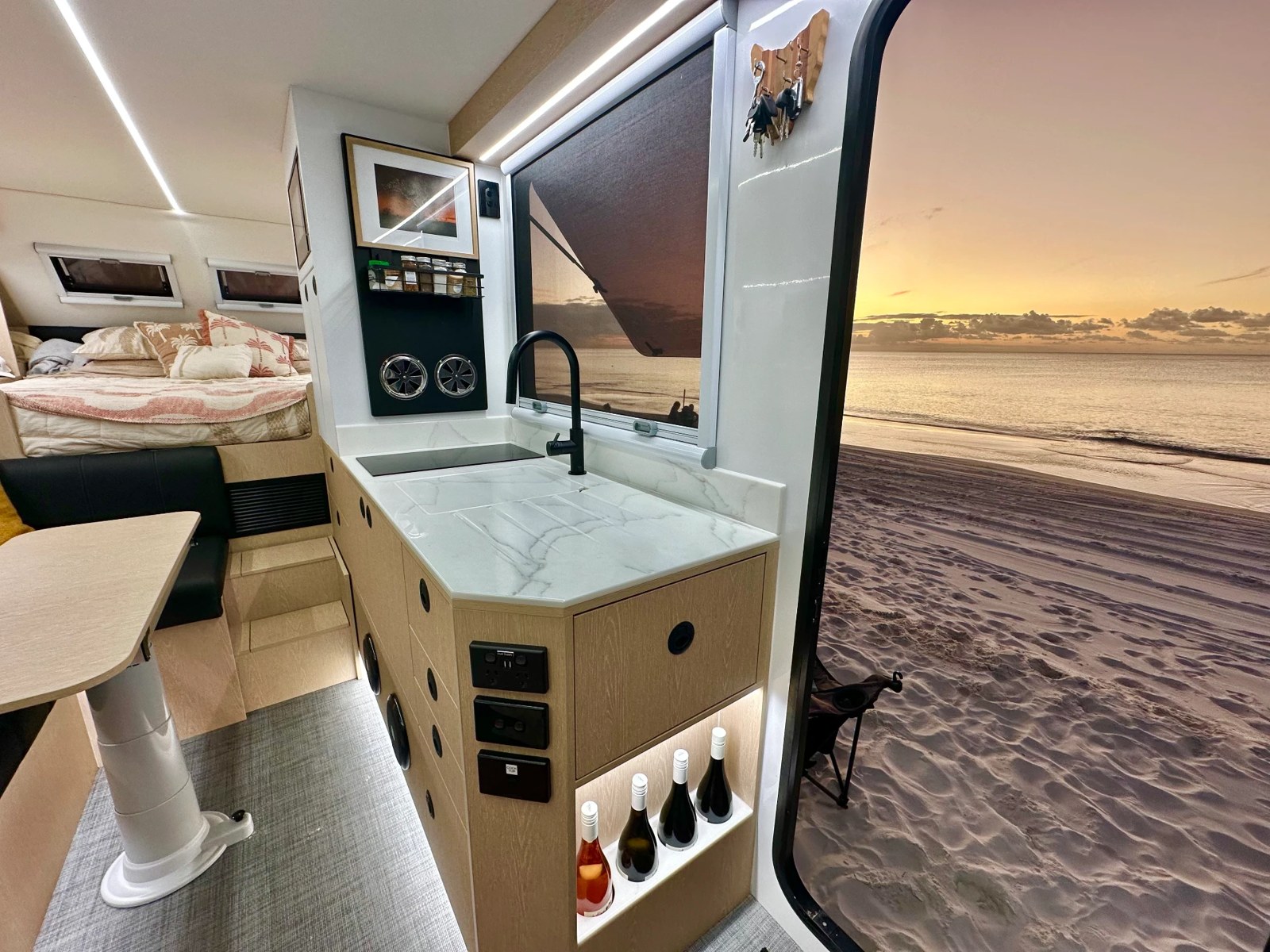 Bruder interior galley with stone benchtop looking out to a beach sunset
