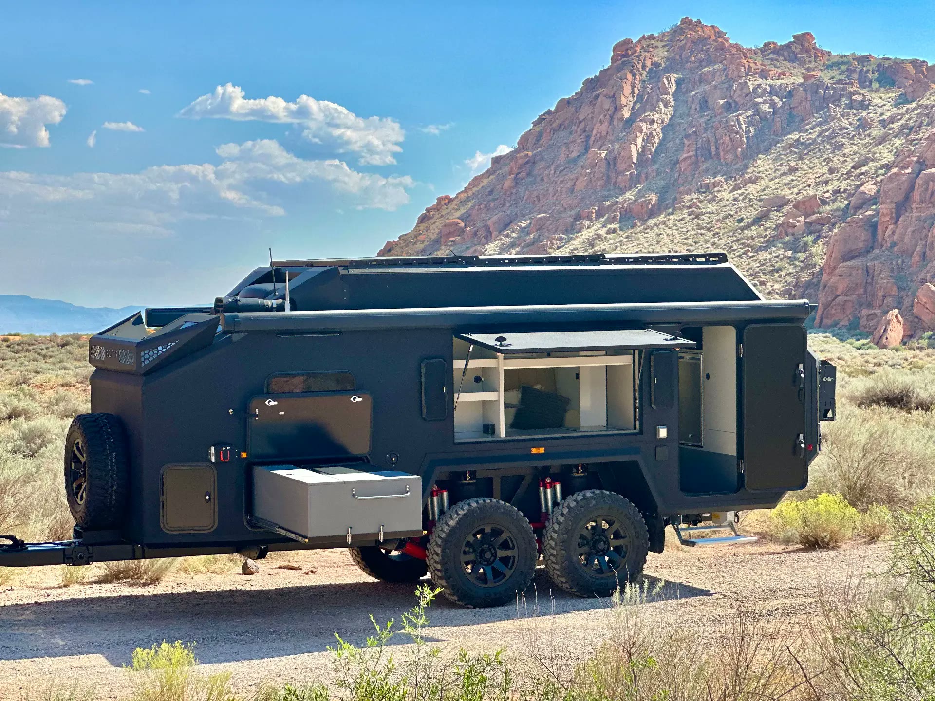 Bruder expedition camper parked on a desert track below red rock cliffs